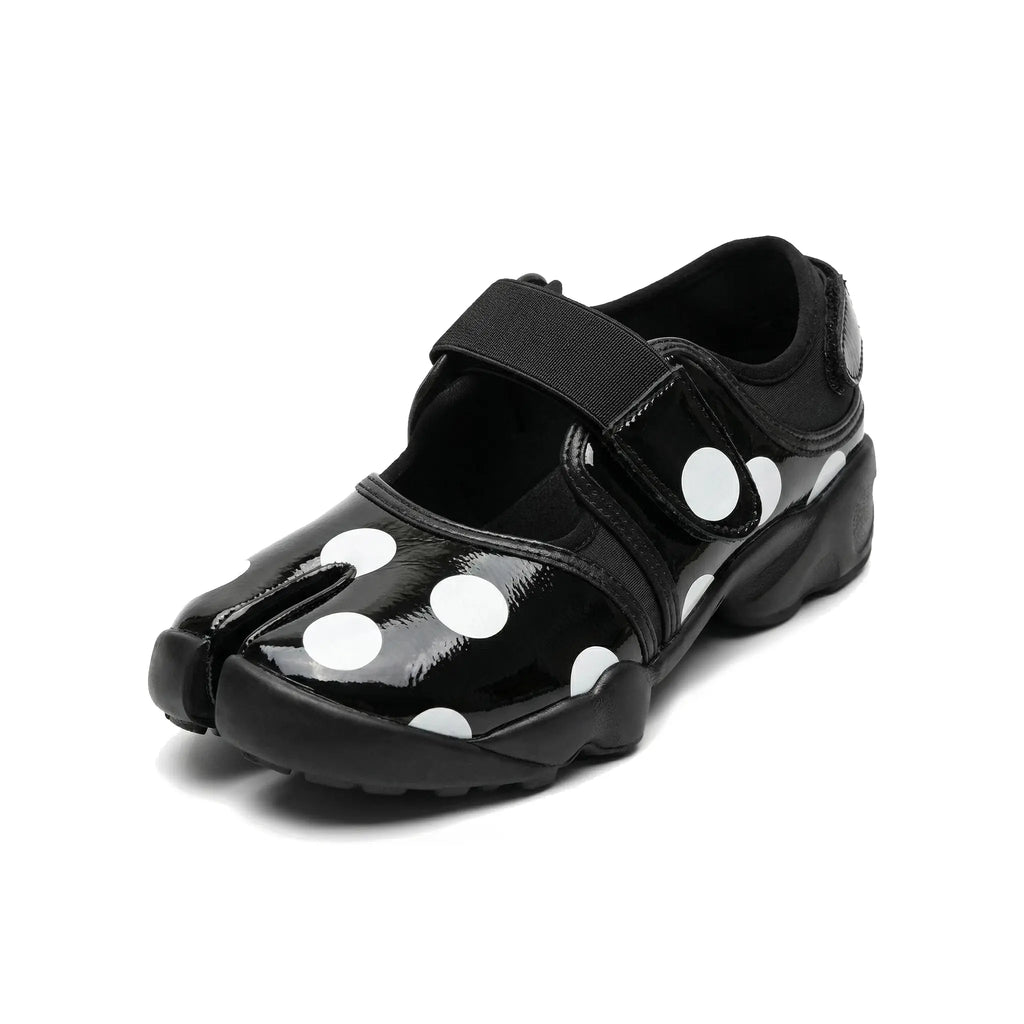 ZQW Dotty Split 2.0 Tabi Mary Jane Sneakers in black with bold polka dots, 45-degree angle view – chunky white dots on black base, split-toe design, hook & loop closure, cushioned sneaker sole