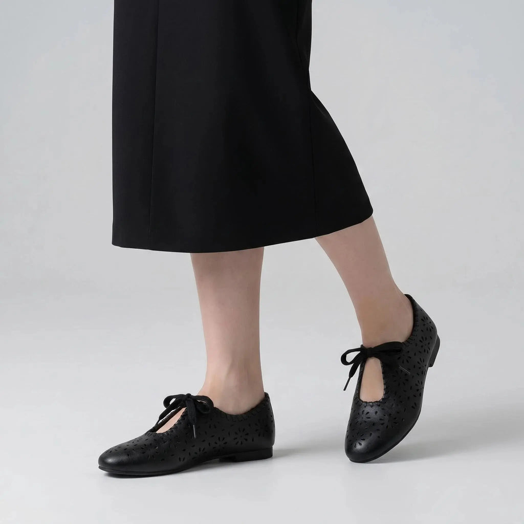ZQW Lace-Up Cutout Floral Mary Janes in black, worn on feet close-up – floral cutout pattern allows breathability, lace-up front for adjustable fit, cushioned insole for all-day comfort